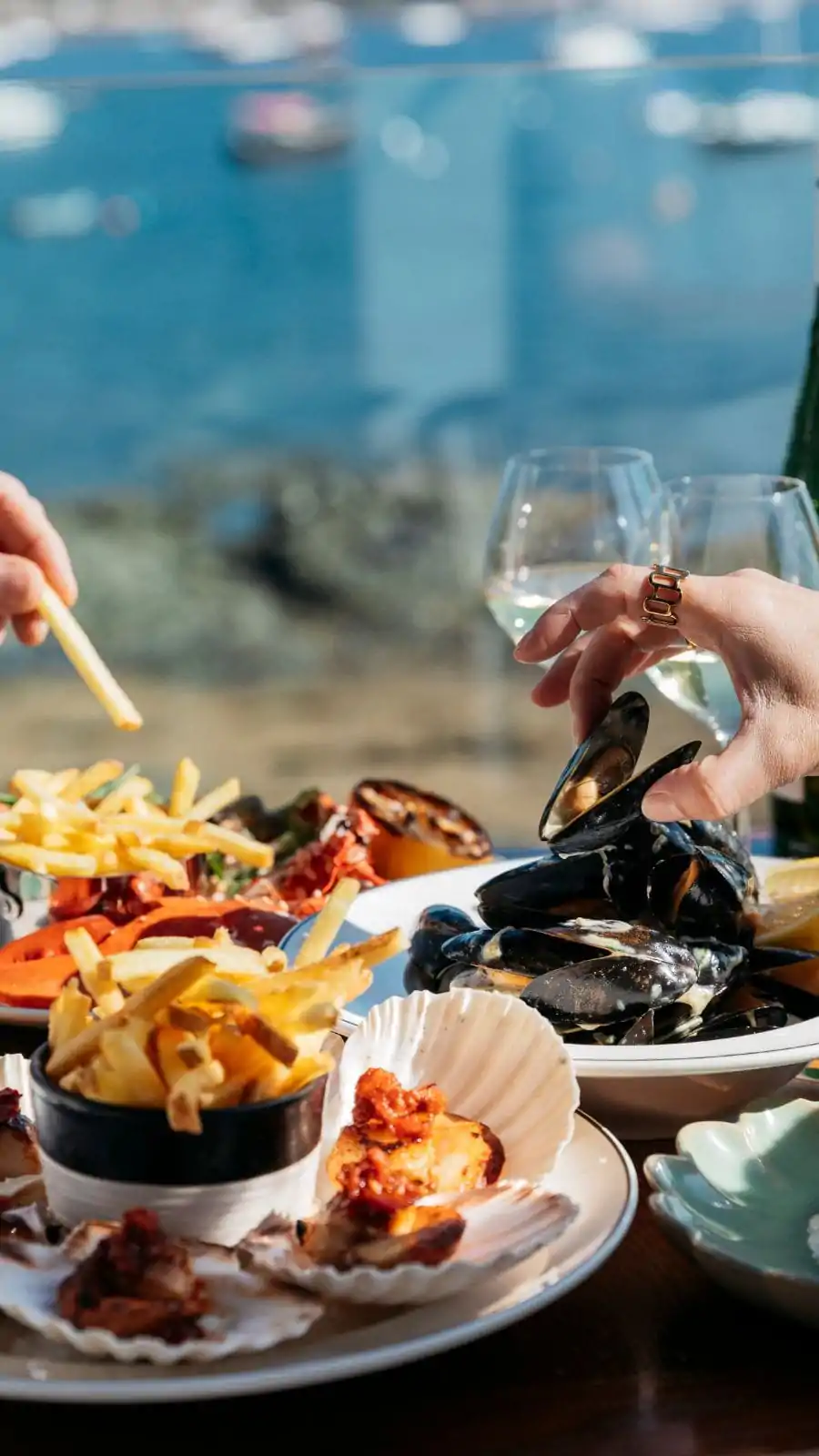 2 customers enjoying lunch on the terrace at INDIDOG, the closest table to waterside dinging in Falmouth - shellfish, mussells, scallops, meat and vegan
