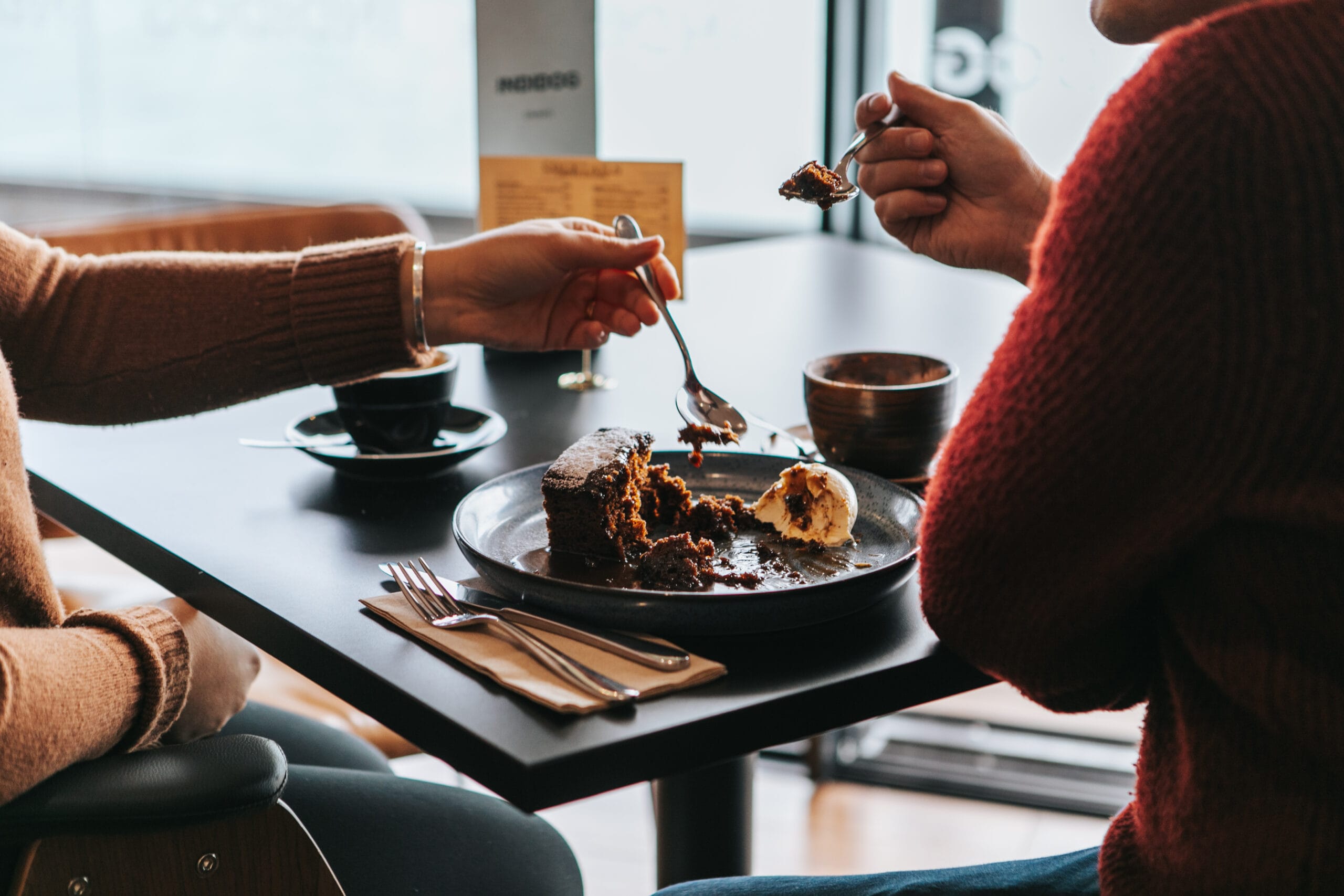 2 Customers sharing an indulgent chocolate dessert on INDIDOG'S Sunday roast service in the harbourside restaurant in Falmouth